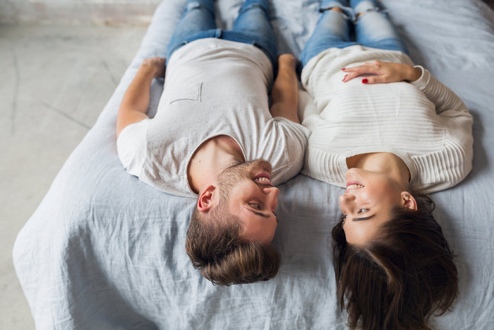 young happy smiling couple sitting on bed at home