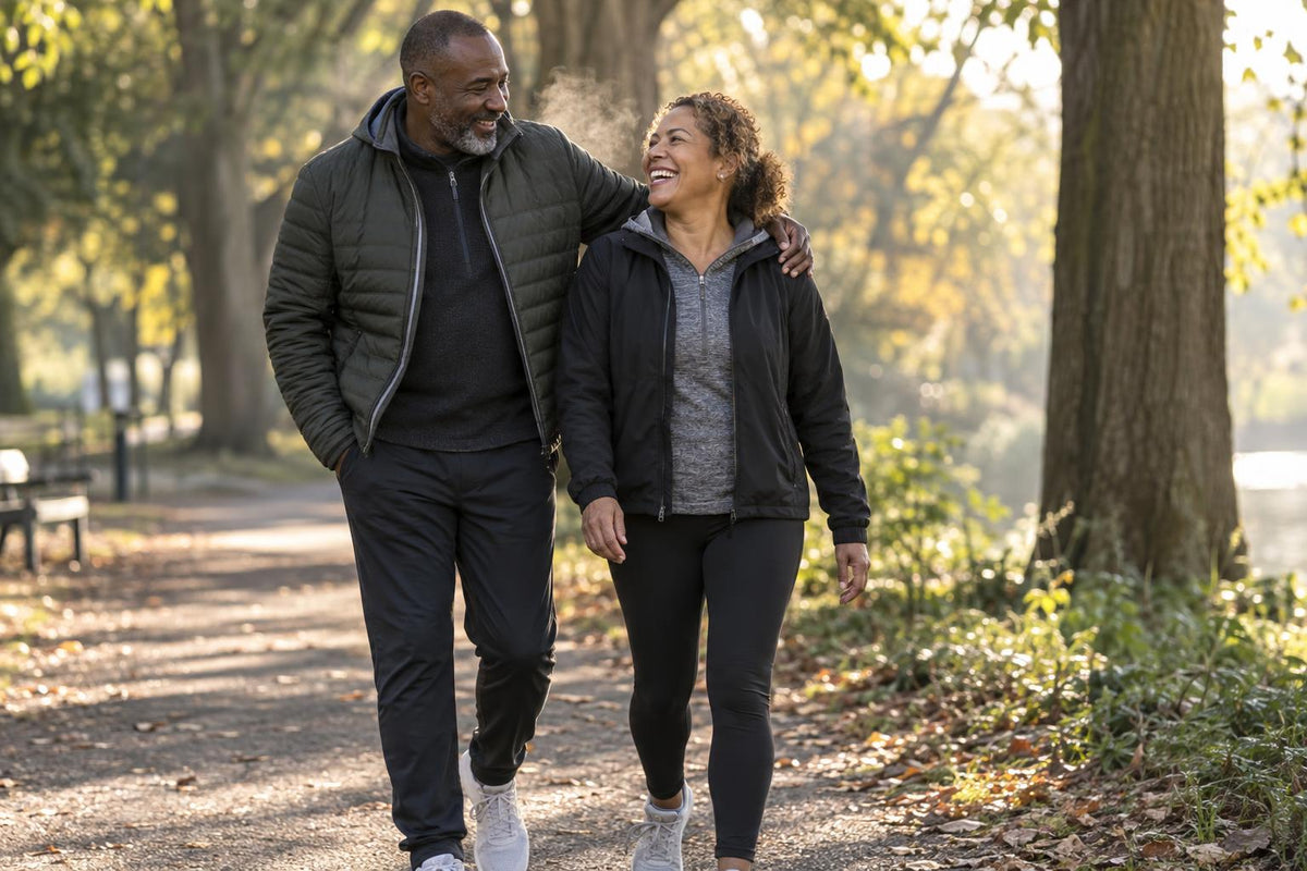 Couple in their late forties walking and laughing together on a sunlit park path
